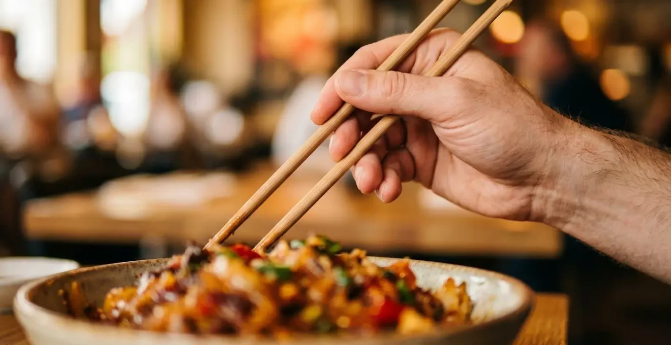 Main tenant des baguettes au-dessus d'un plat coloré en gros plan