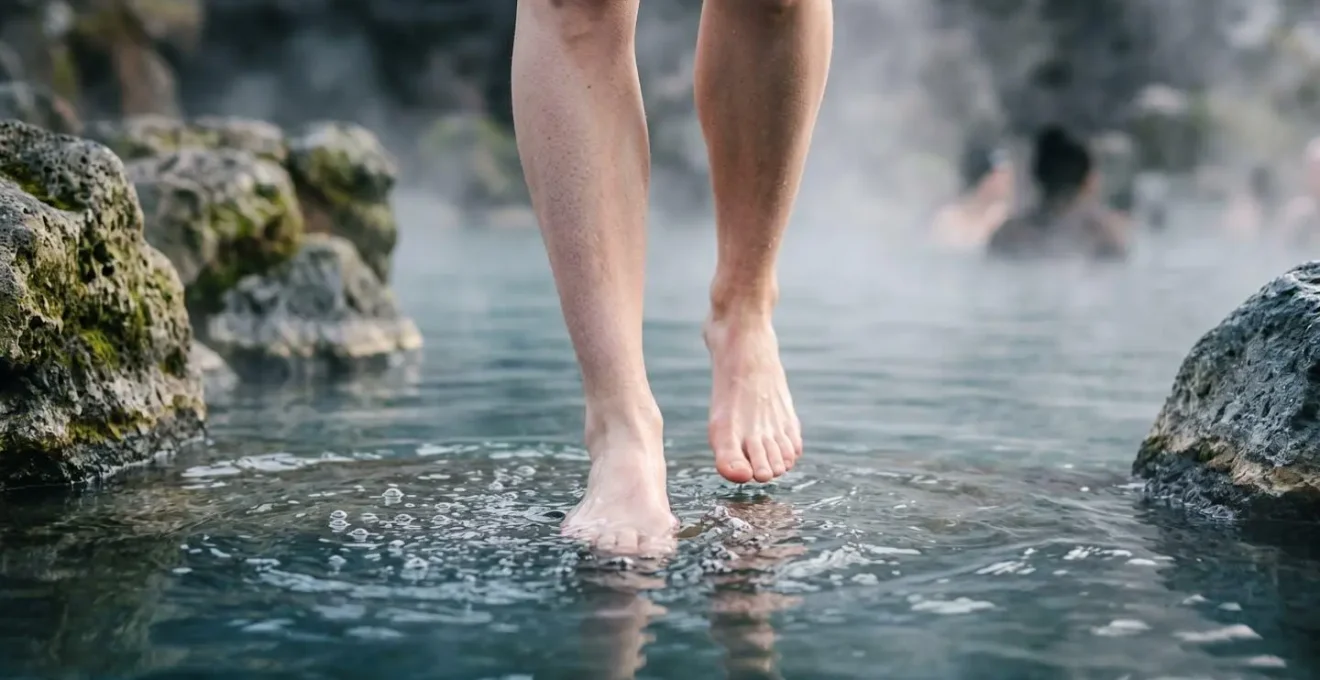 Personne entrant progressivement dans une source chaude en immergeant d'abord ses pieds et chevilles