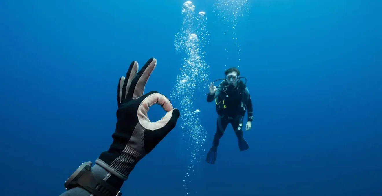 Plongeur démontrant les signes universels de communication sous l'eau avec ses mains