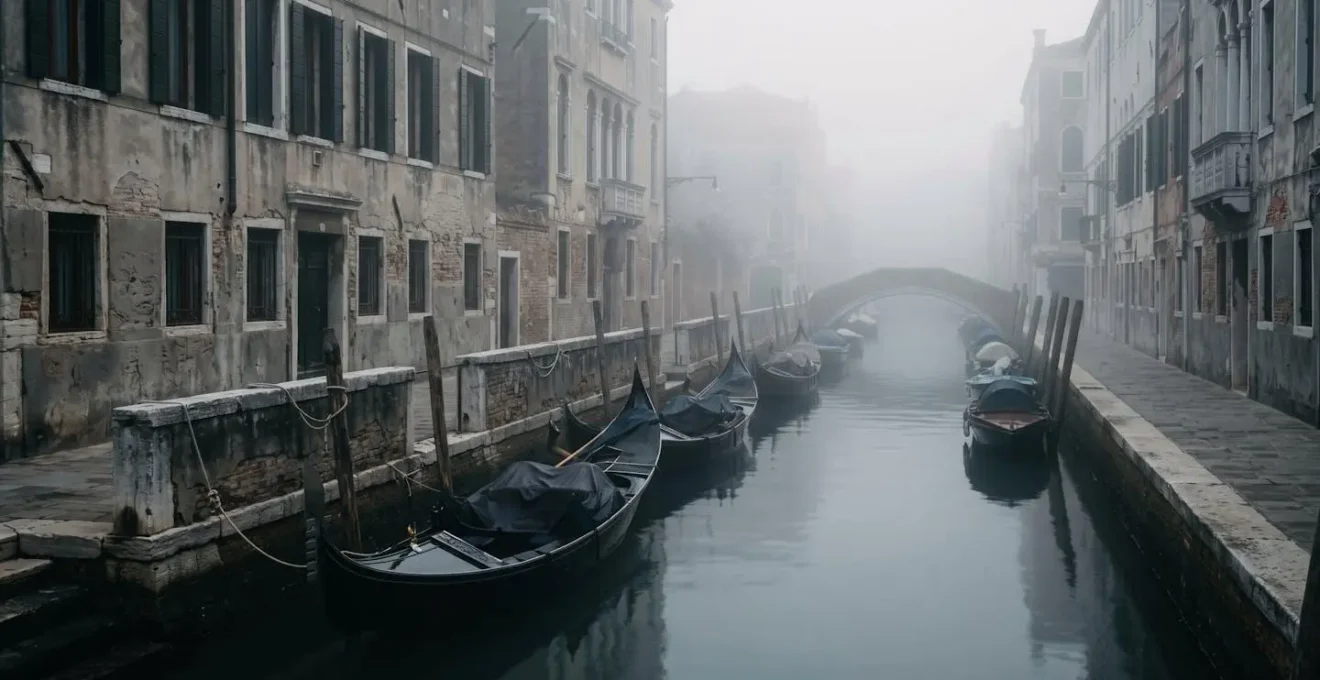 Canal vénitien désert dans la brume matinale d'hiver avec gondoles amarrées